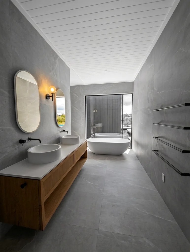 Luxurious high-end tiled bathroom with a freestanding bath and large picture window framing the Matakana landscape in a colour pop